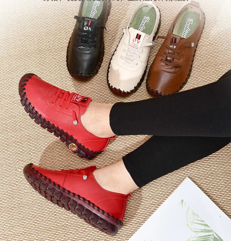Red shoes worn by a person on a beige carpet with other shoes in the background.