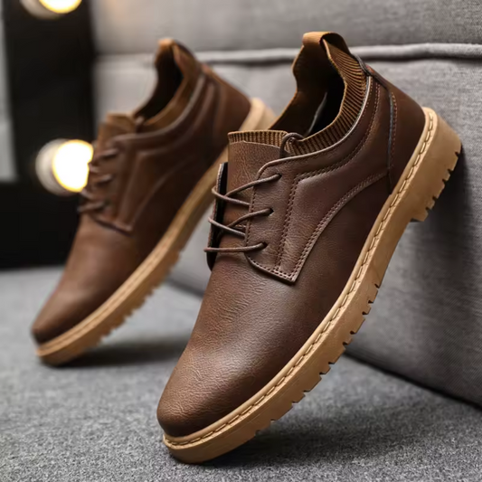 Brown leather shoes on a gray surface with blurred lights in the background