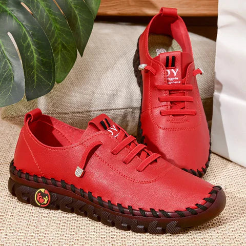 Red sneakers with black soles on a textured surface