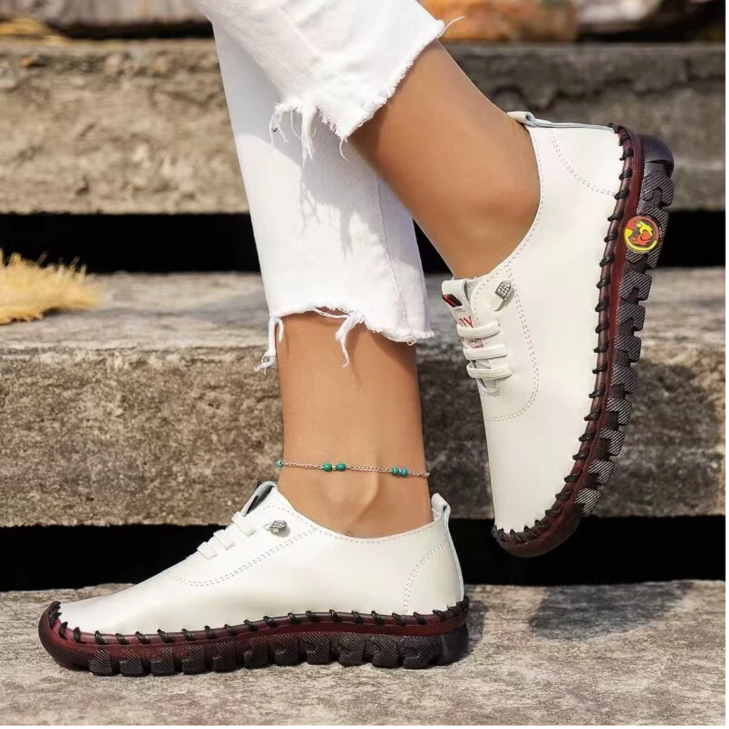 White sneakers with red soles worn by a person sitting on steps.