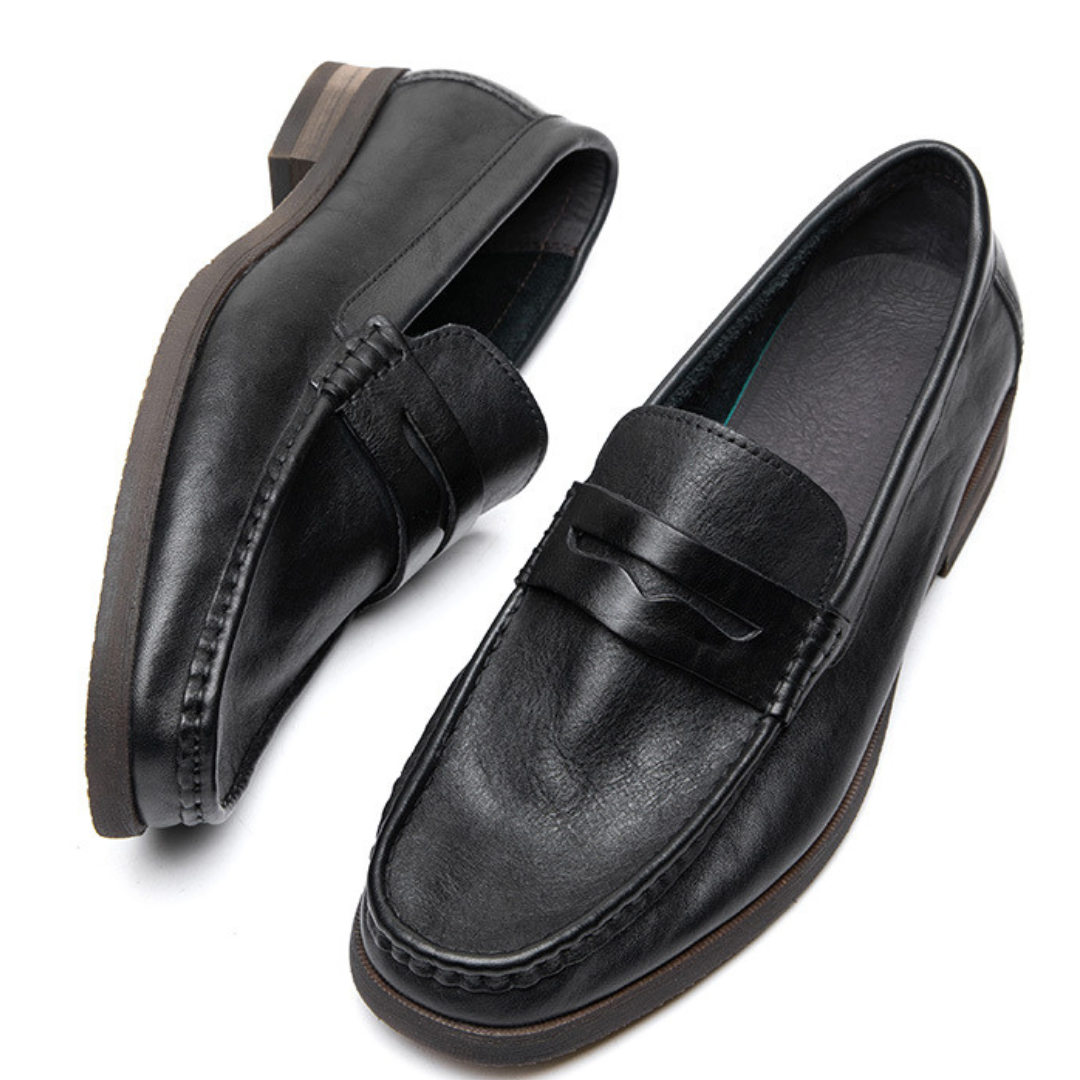 Pair of black leather loafers on a white background